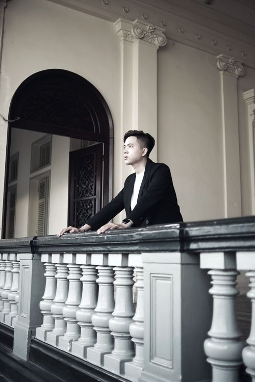 Free A man stands thoughtfully on a historic balcony in Ho Chi Minh City, Vietnam. Stock Photo