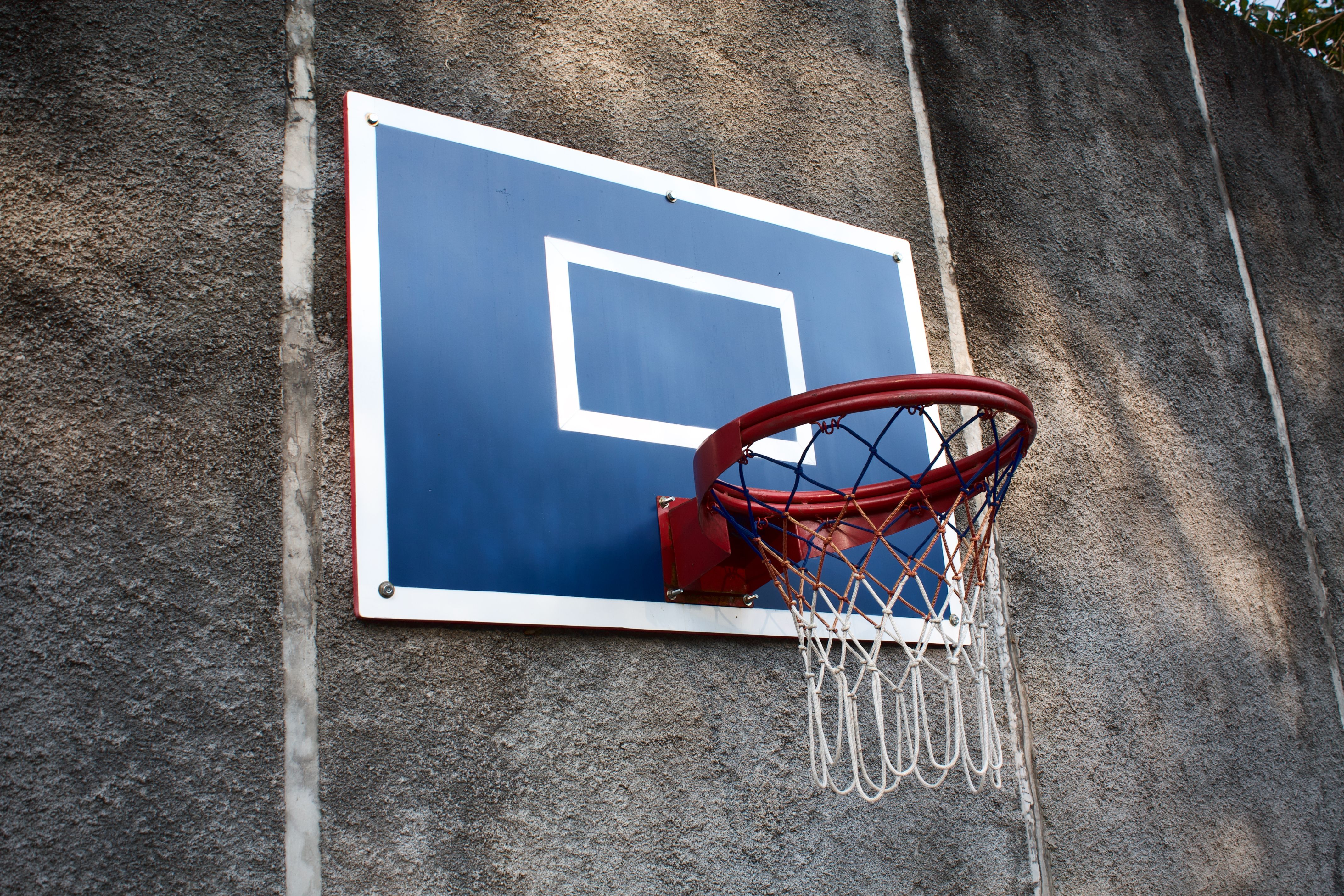 A basketball hoop mounted on a concrete wall under sunlight, ideal for sports-related themes.