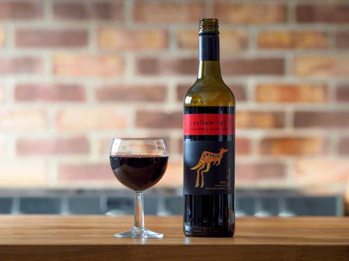 Close-up of a Bottle and Glass of Red Wine Standing on a Table 