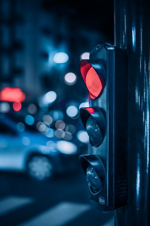 Free A traffic light glows red on a bustling Rabat street at night with blurred city lights. Stock Photo