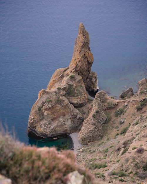 Free Stunning eroded rock formations along a serene seashore with clear blue waters. Stock Photo