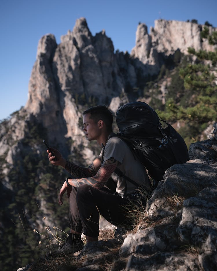 Backpacker Using Smartphone In Mountains