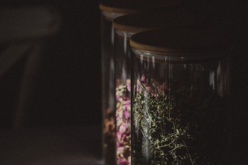 Free Dark and atmospheric close-up of glass jars filled with spices and herbs in low light. Stock Photo
