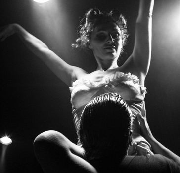 Black and white photo of a dramatic dance performance under spotlights.