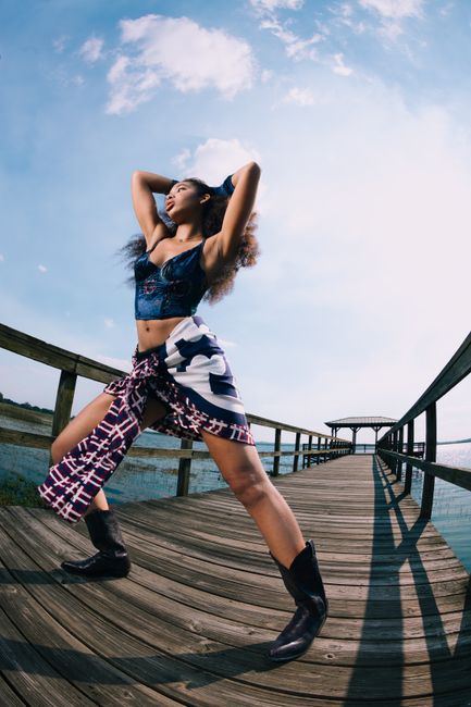 Woman in fashionable attire poses confidently on a pier by a lake in Orlando, Florida.