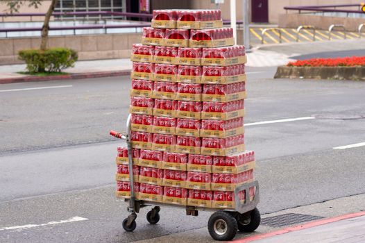 Stacked Coca Cola cans on a delivery cart in a city street, showcasing urban distribution.