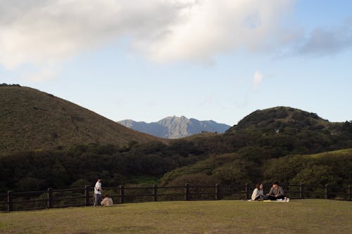 People Sitting on the Grass in a Park with View of Mountains 