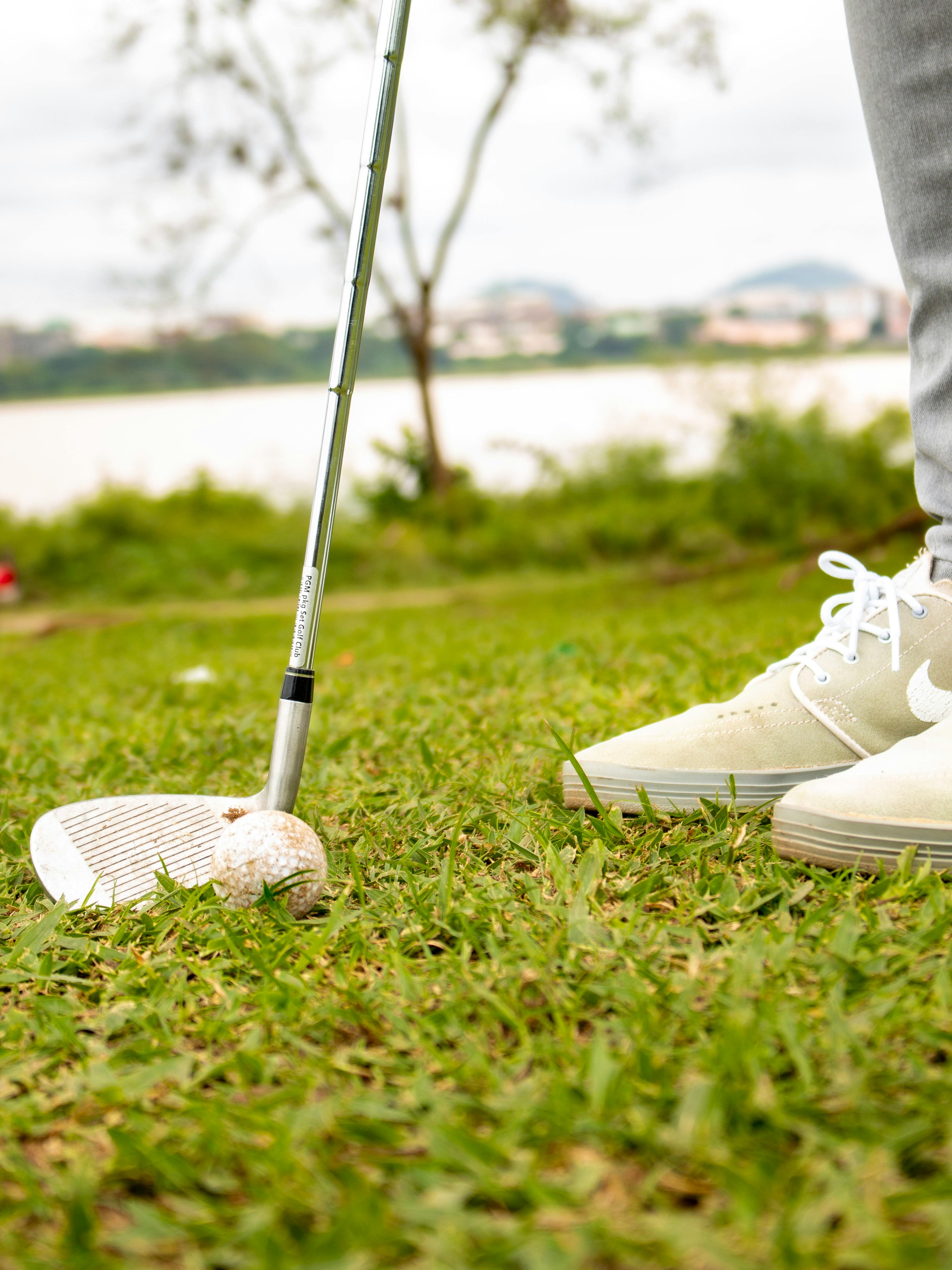 A golfer prepares to hit a golf ball on a vibrant green lawn with scenic background.