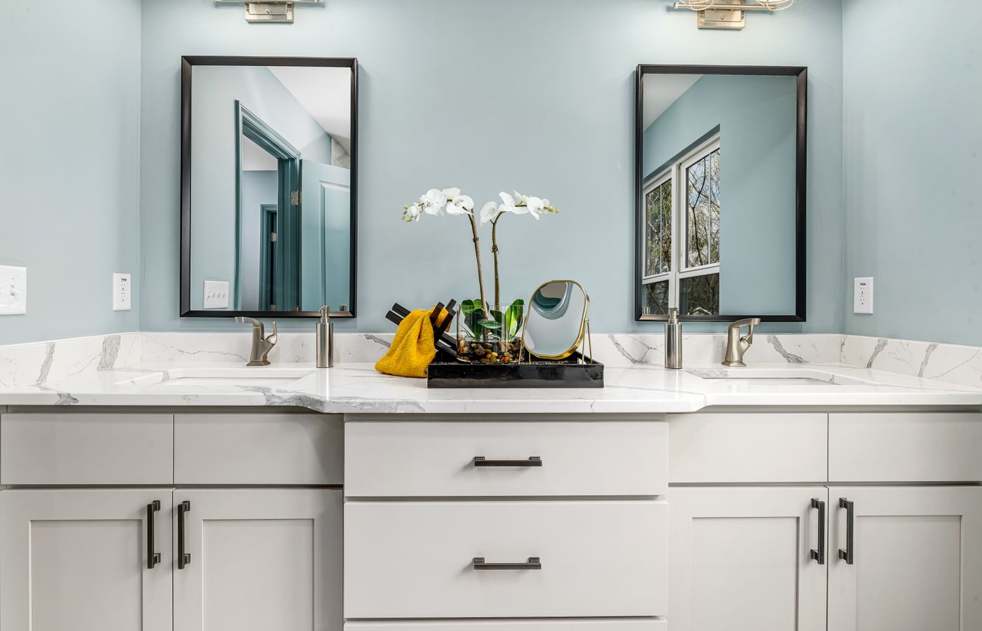 A serene modern bathroom featuring twin sinks, elegant faucets, and decorative mirrors.
