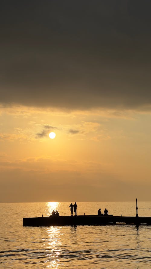 Silhouettes of People on a Pier in the Evening 