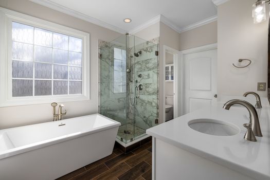 Bright and elegant bathroom featuring a glass shower, bathtub, and chic fixtures.