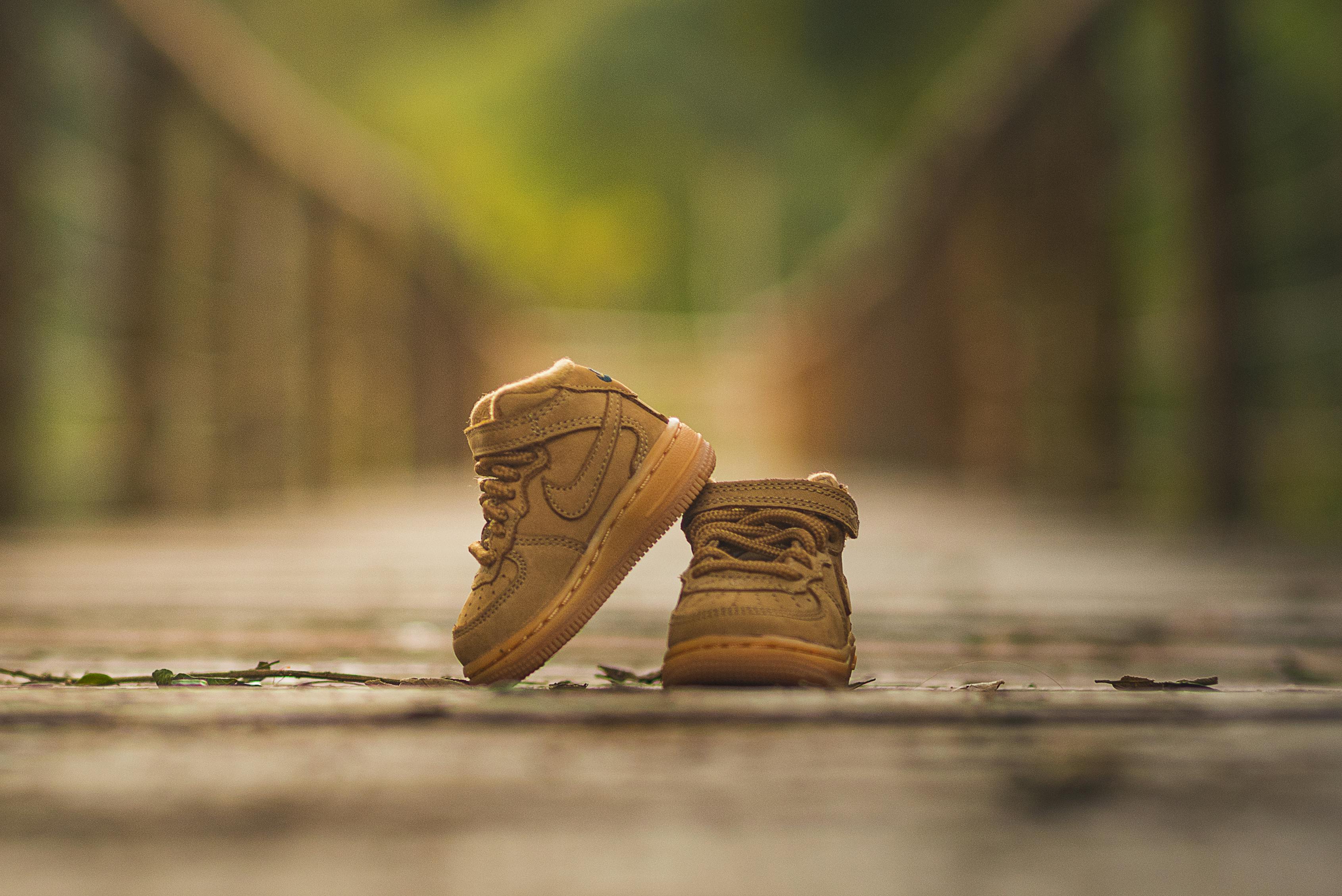 Adorable pair of tiny baby shoes on a sunlit wooden path, capturing a warm and inviting outdoor scene.