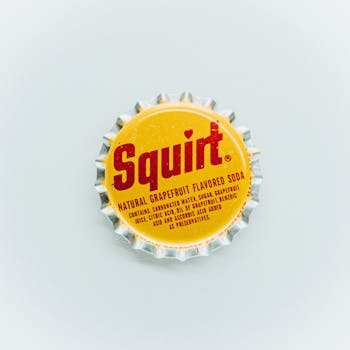Close-up of a vintage Squirt grapefruit soda bottle cap, isolated on white.