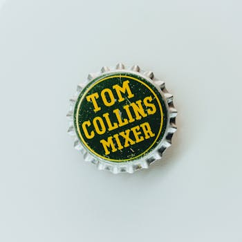 Closeup of a vintage Tom Collins Mixer bottle cap on white background, showcasing classic design.