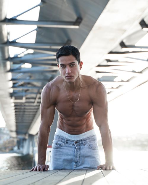 Free A muscular shirtless man poses confidently under a bridge in Istanbul, showcasing fitness and strength. Stock Photo