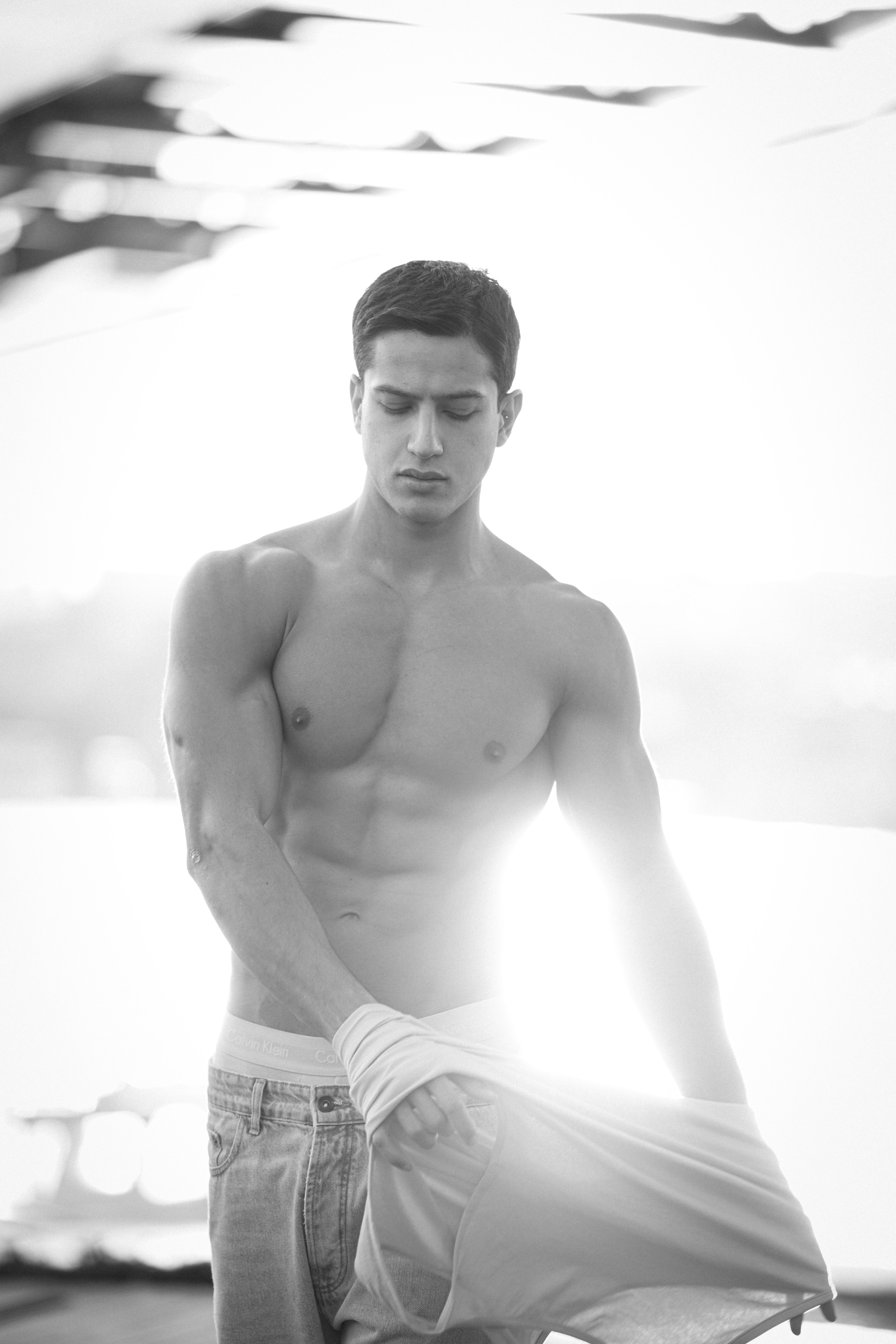 Striking black and white portrait of a muscular man posing shirtless outdoors in Istanbul.