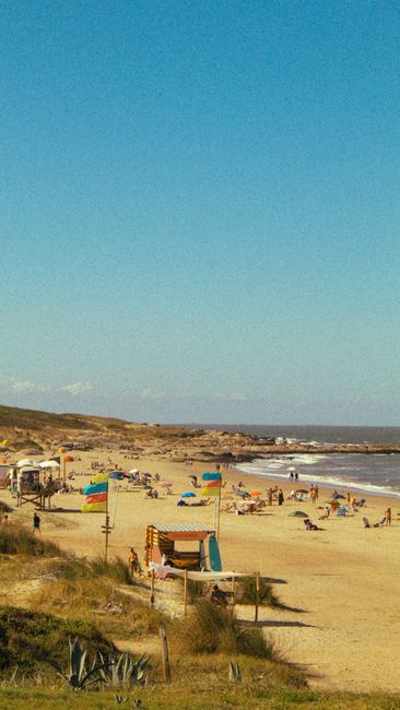 Fotomural Una vibrante escena de playa de verano en Punta del Diablo, Uruguay, capturando actividades animadas en la costa.