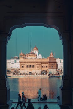 View of the Golden Temple reflected in water, framed by an archway in Amritsar, India.