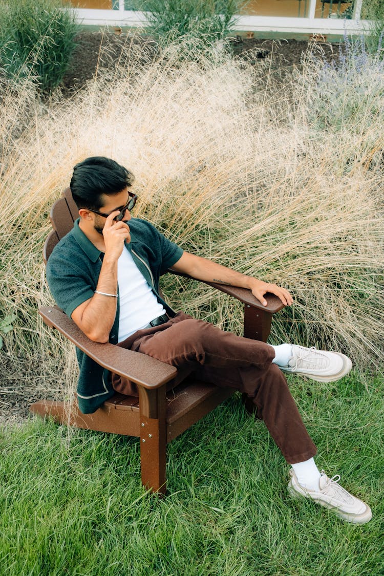 Stylish Man In Sunglasses Sitting On Chair In Garden