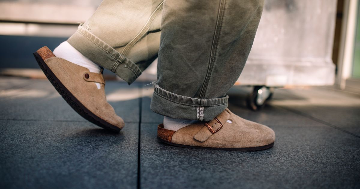 A person wearing brown sandals photographed from above.