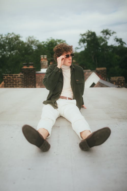 Man with Sunglasses in Black Shirt Sitting on Rooftop