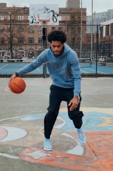Athlete playing basketball outdoors on a city court with vibrant urban art.