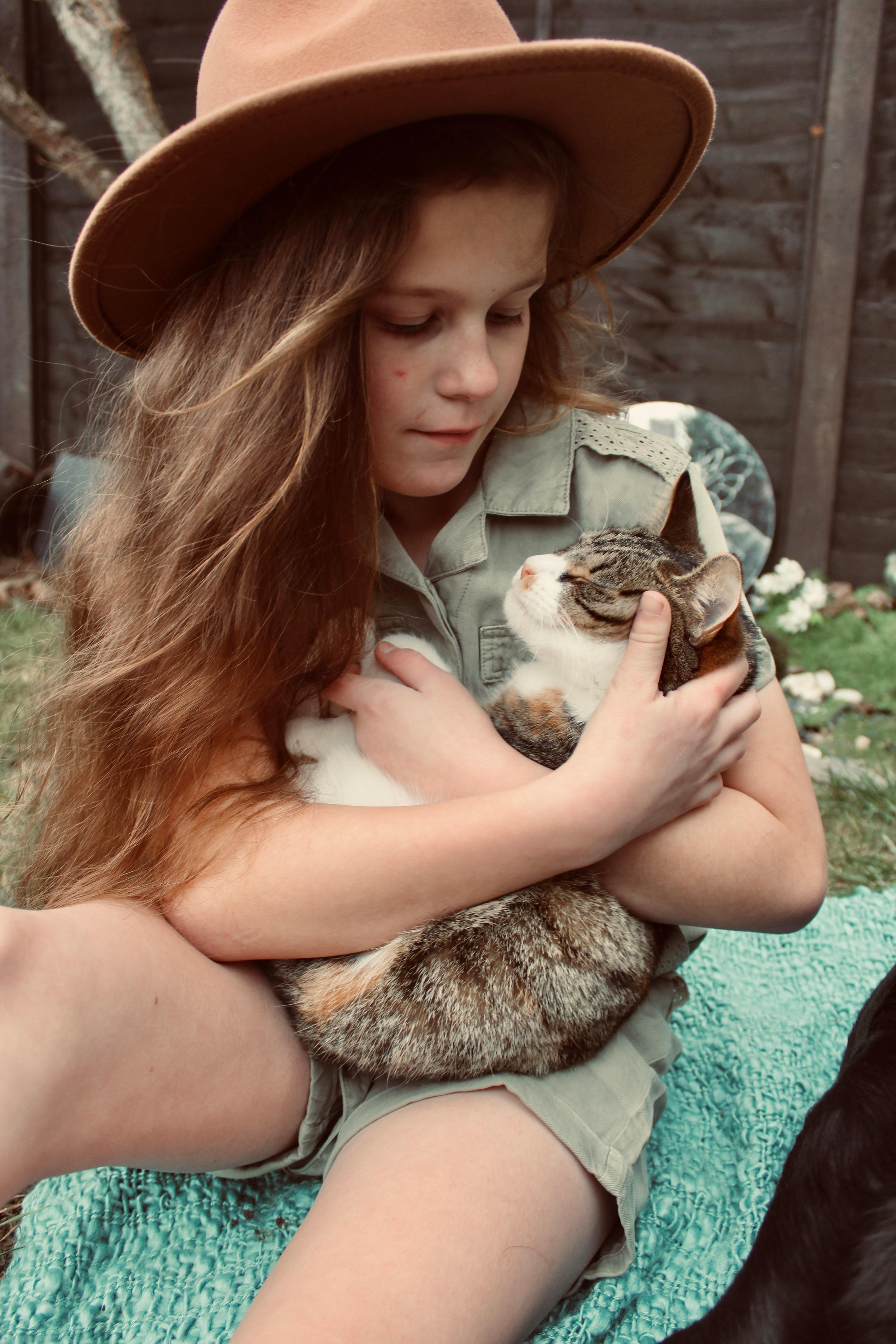 a girl sitting outdoors and holding a kitten