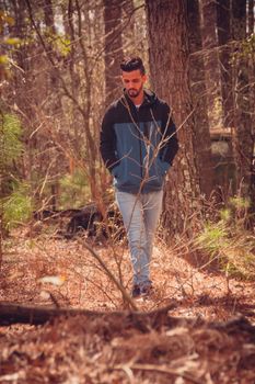A man enjoying a peaceful walk in a sunlit autumn forest, surrounded by nature.