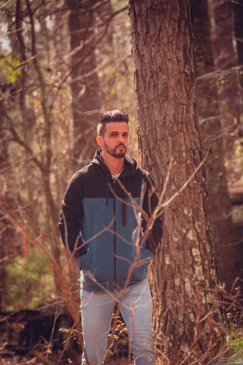 Free Young man casually walking through a serene forest, enjoying nature. Stock Photo
