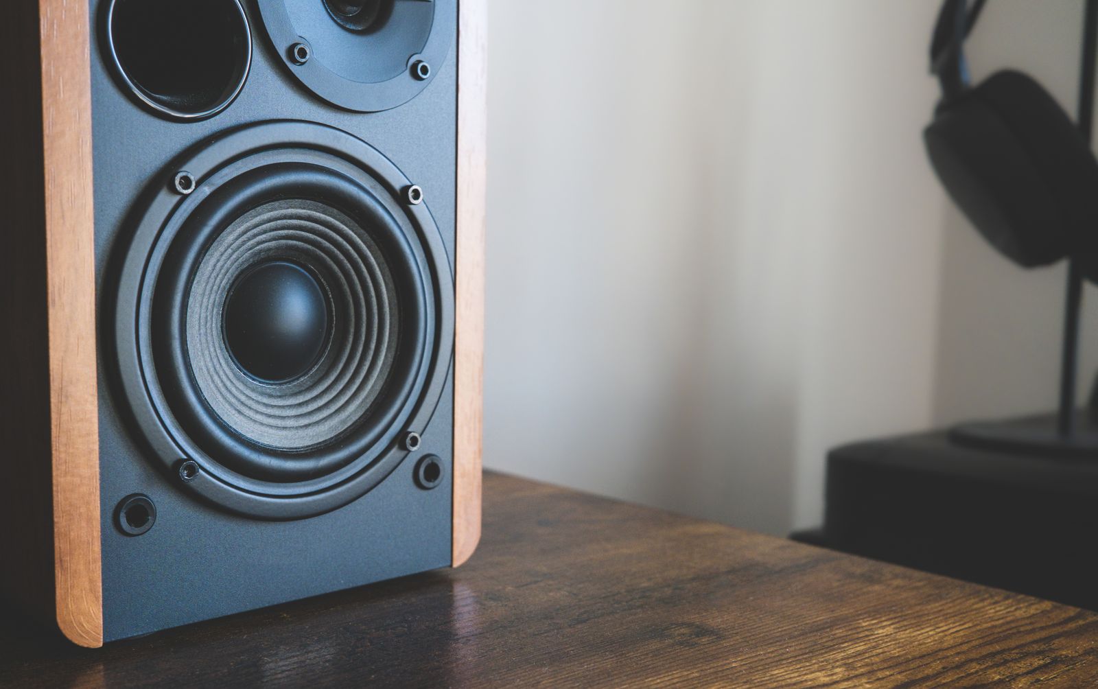 Speaker and headphones arranged on a wooden surface.