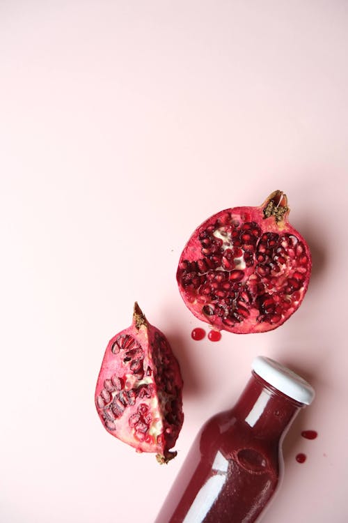 Pomegranate and Bottle of Juice on Pink Background