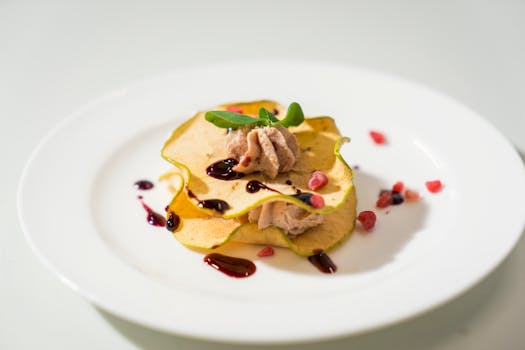 A stylishly presented dessert on a white plate, adorned with fresh garnishes and a drizzle of sauce.