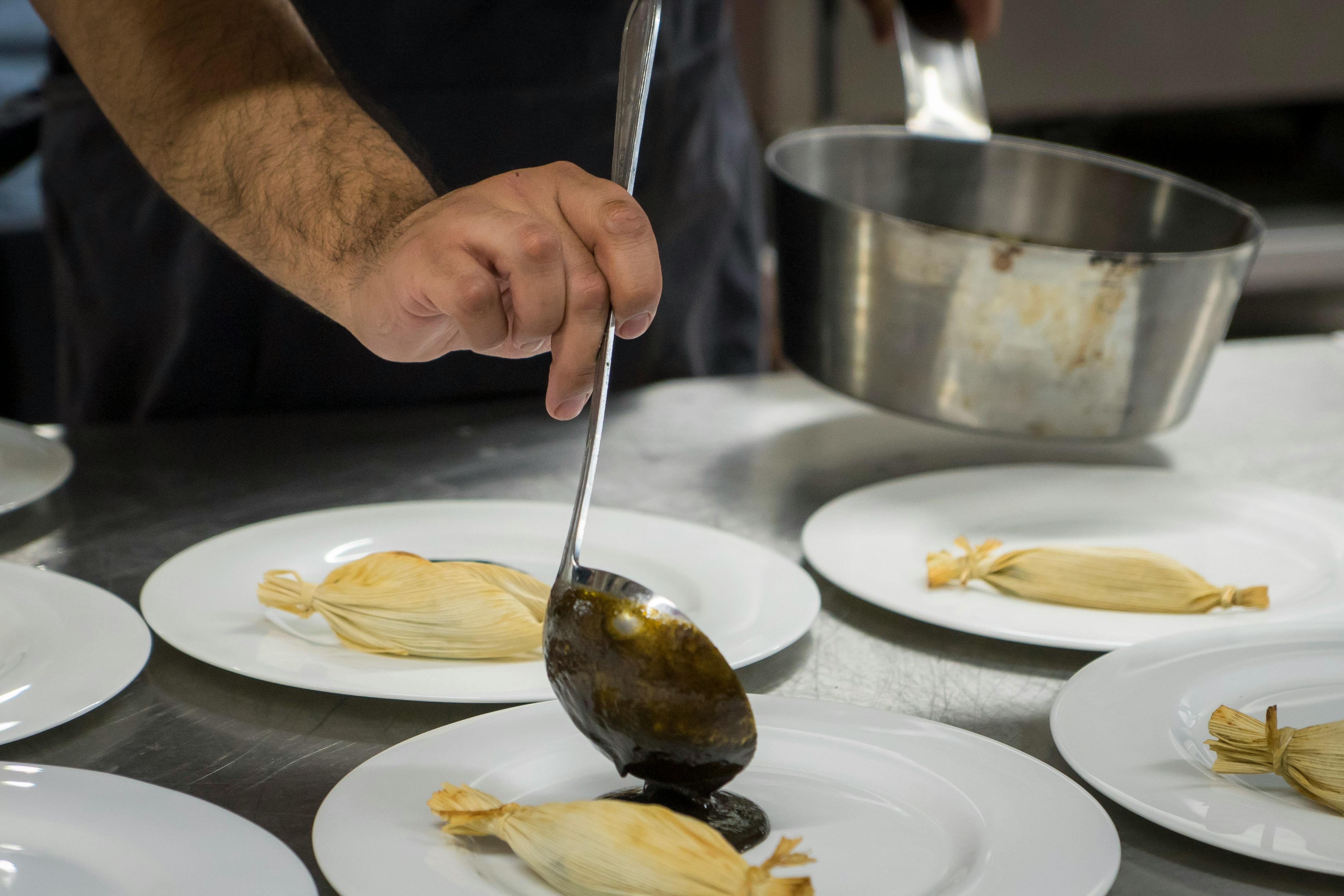 https://images.pexels.com/photos/15671409/pexels-photo-15671409/free-photo-of-hand-with-kitchen-spoon-over-plates-with-food.jpeg