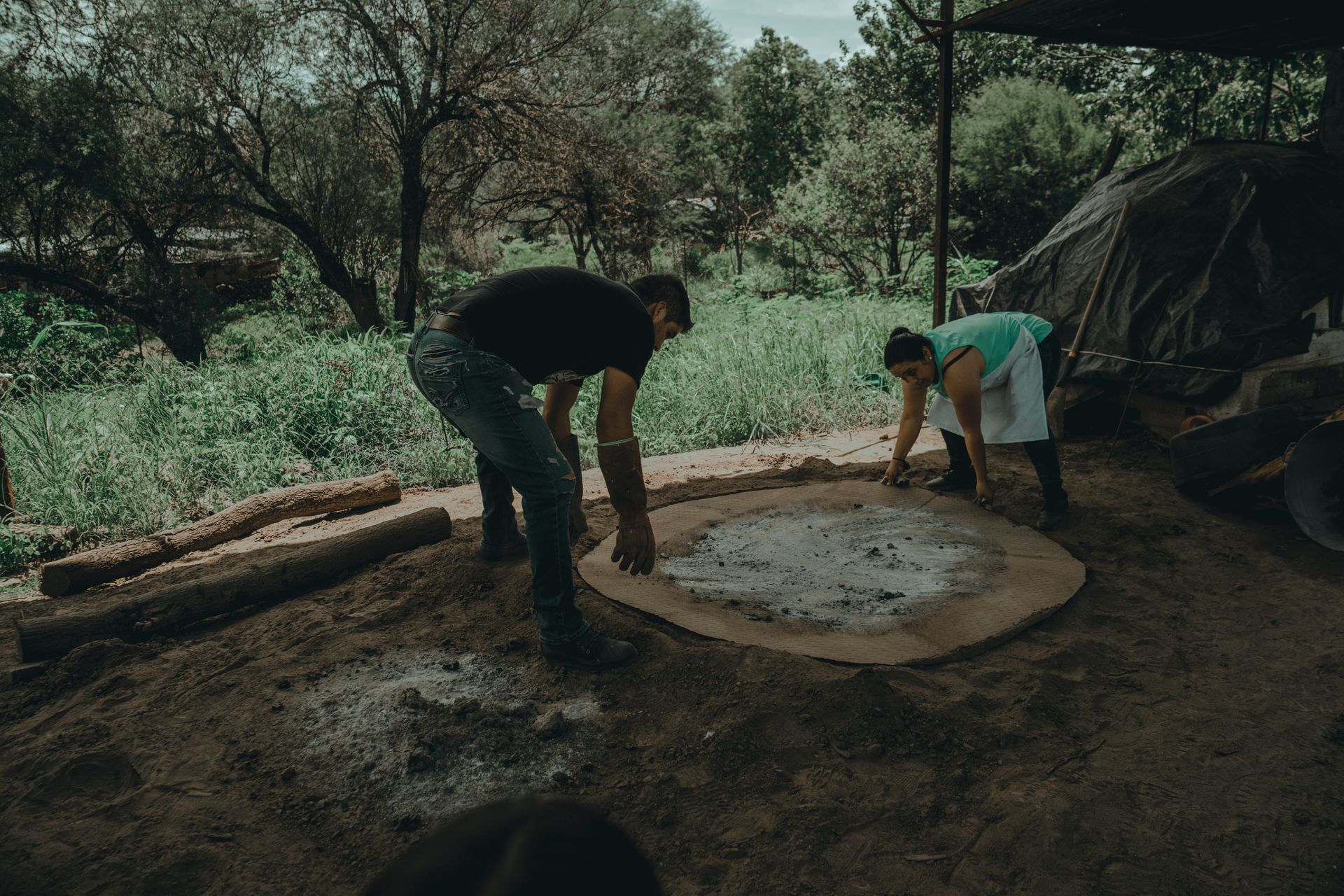 Man and woman cleaning a fireplace in a rural farm setting, outdoors.