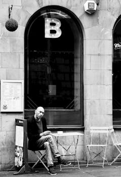A man enjoys a coffee at an outdoor cafe in the urban streets of Kilsby, England.