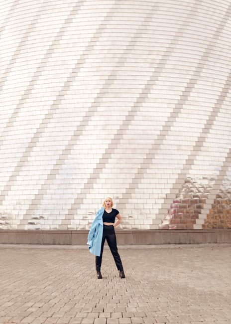 Fashionable woman poses against a contemporary metallic facade in Des Moines. Perfect for urban and architectural themes.