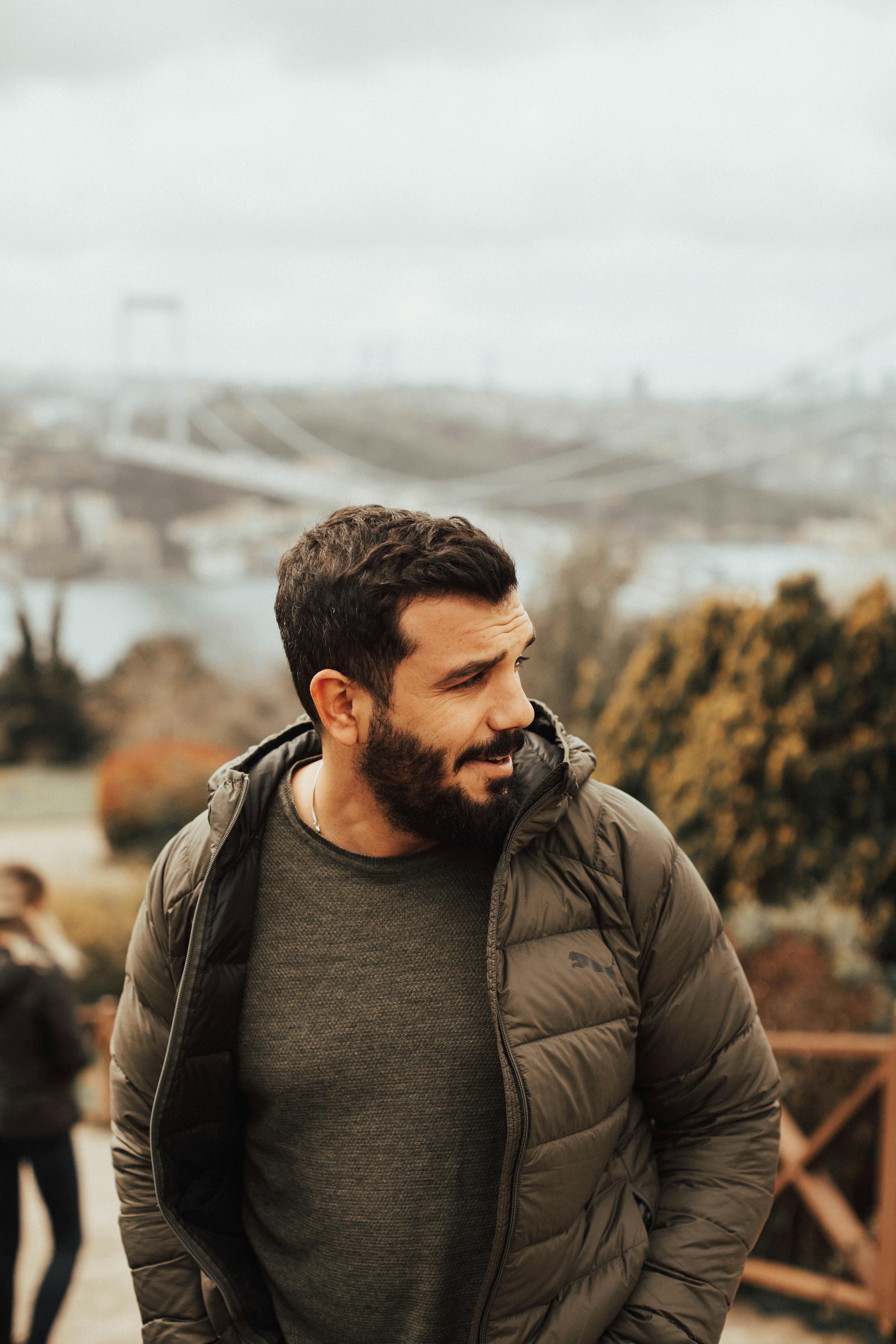 Man with a beard in a jacket enjoys an outdoor view in Türkiye.