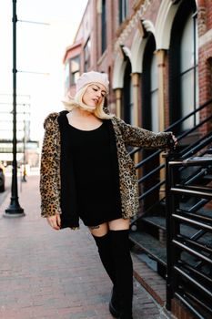Stylish woman posing in leopard print coat on Des Moines sidewalk.