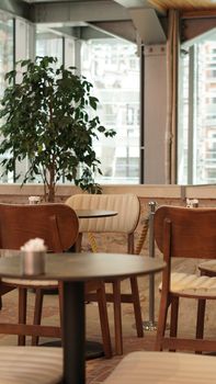 Stylish indoor cafe with wooden chairs, tables, and large windows offering a cozy ambiance.