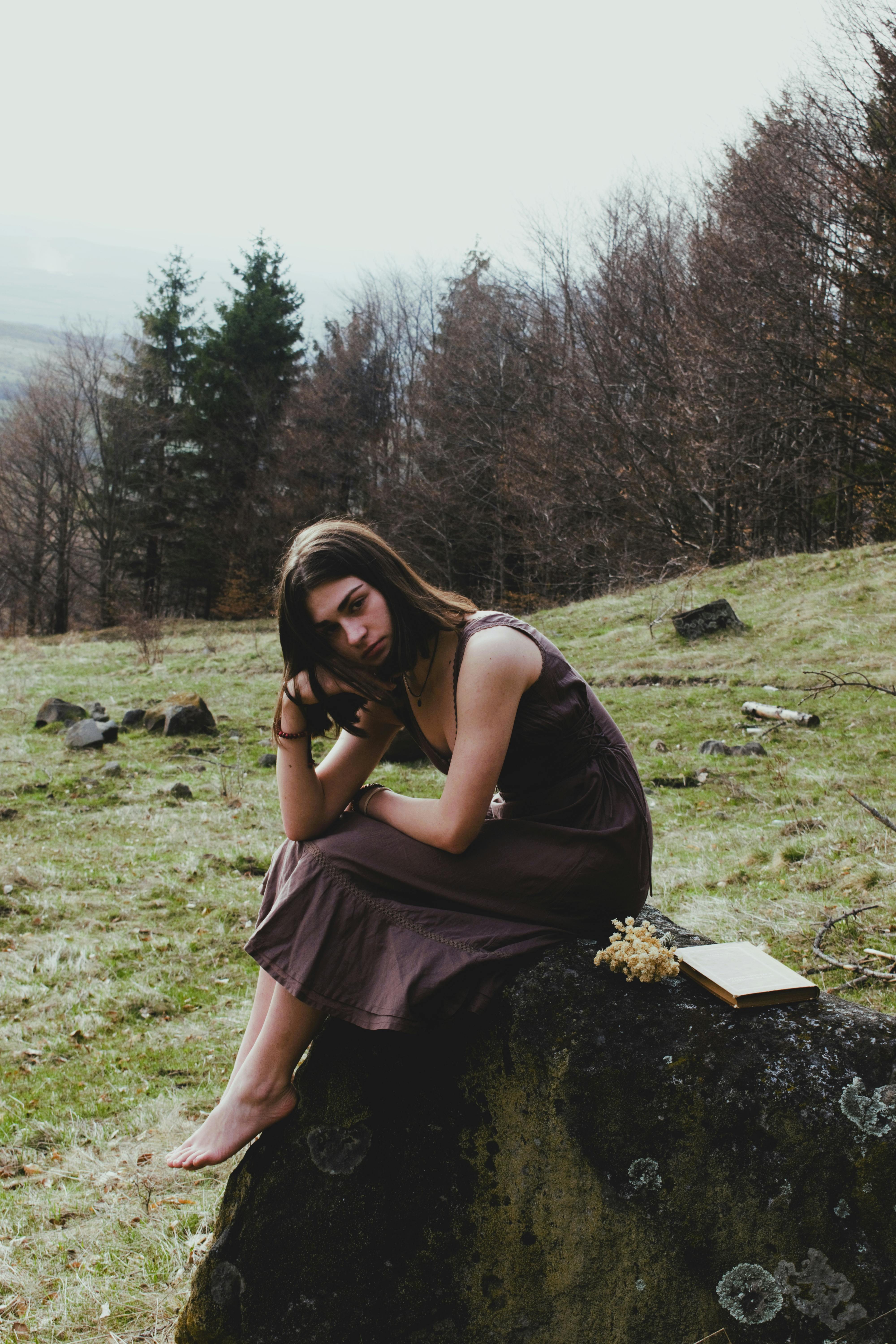 a woman sitting on a rock in the woods