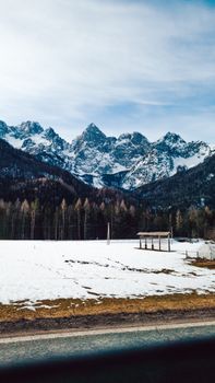 Breathtaking view of snow-covered mountains and a rural Slovenian landscape during winter.