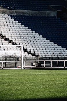 A quiet moment in a stadium with empty bleachers and a visible goal post.