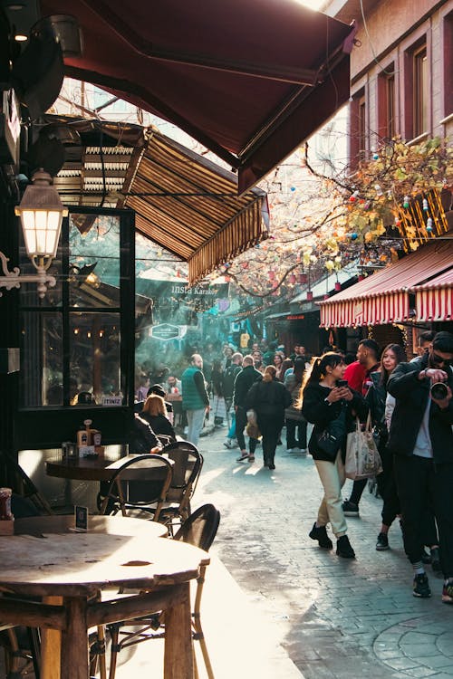 People Walking on Street Along Restaurant in City