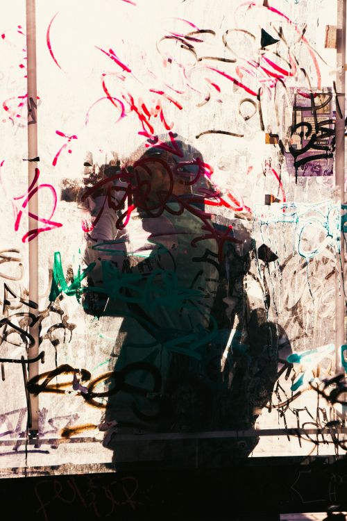 Free Artistic silhouette of a photographer captured through a vibrant graffiti-covered window. Stock Photo