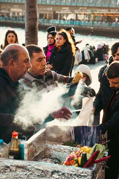 Bustling outdoor market with steaming street food stall, serving a diverse crowd.