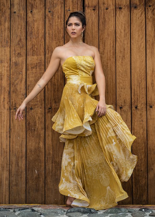 Female Model Wearing a Yellow Dress Posing in Front of a Wooden Wall