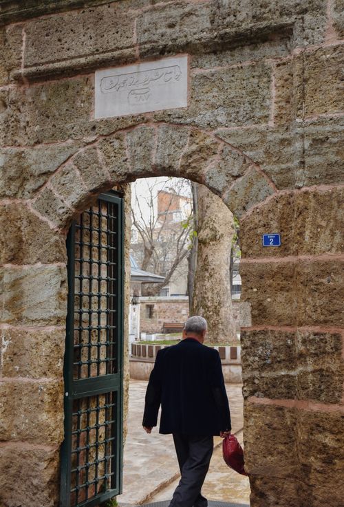Free A senior man walking through a historic stone gate in Kocaeli, Türkiye on a cool day. Stock Photo