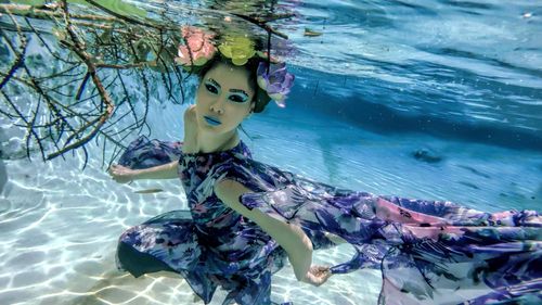 Free Captivating underwater portrait of a young Asian woman in floral attire with striking makeup. Stock Photo