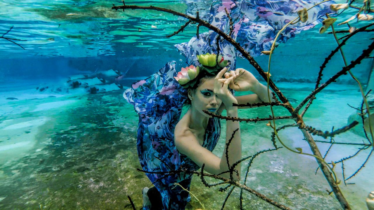 artistic underwater scene of a woman in a floral dress and flower head
