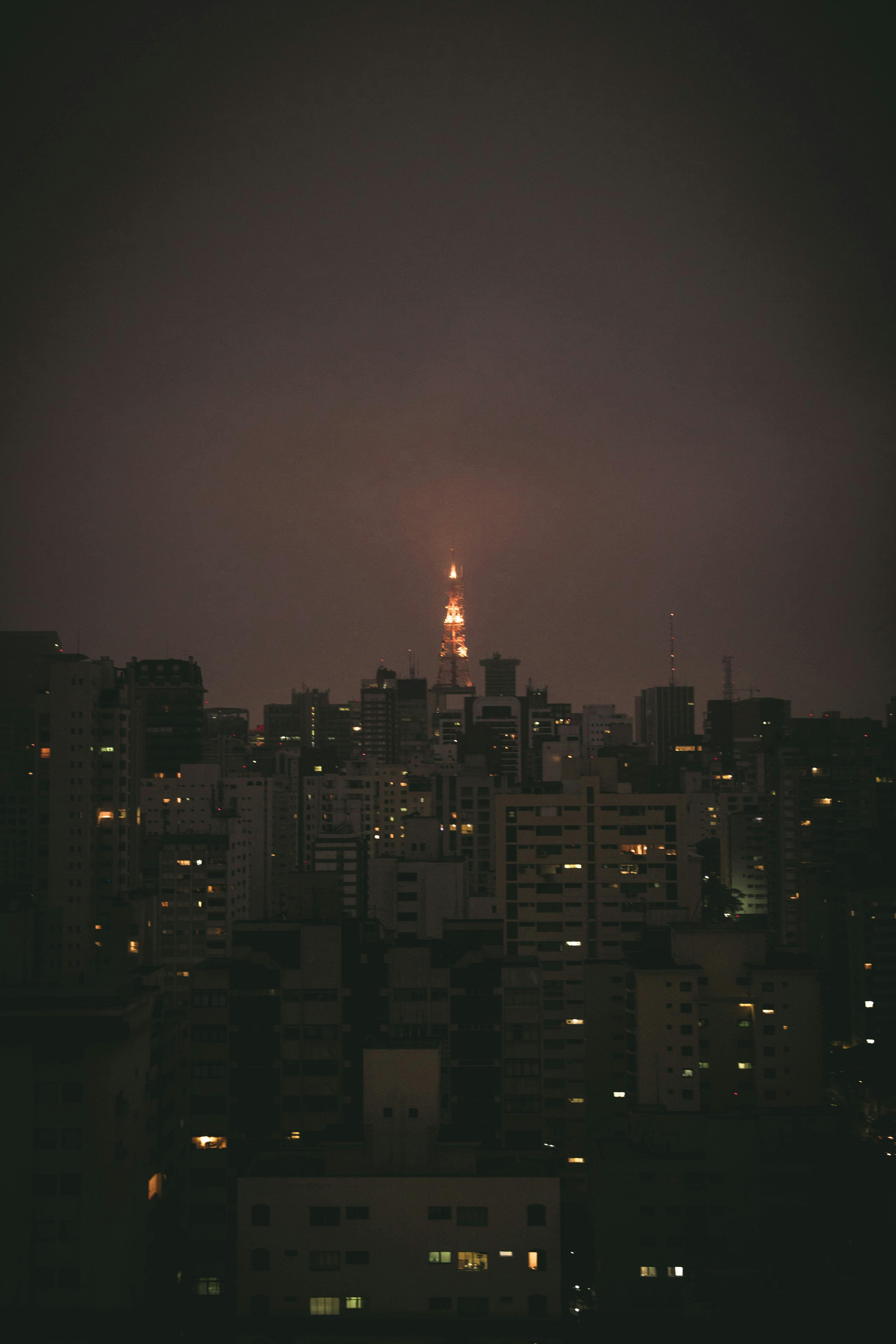 夜晚，一座发光的塔楼在城市建筑中若隐若现，为天际线增添了戏剧性